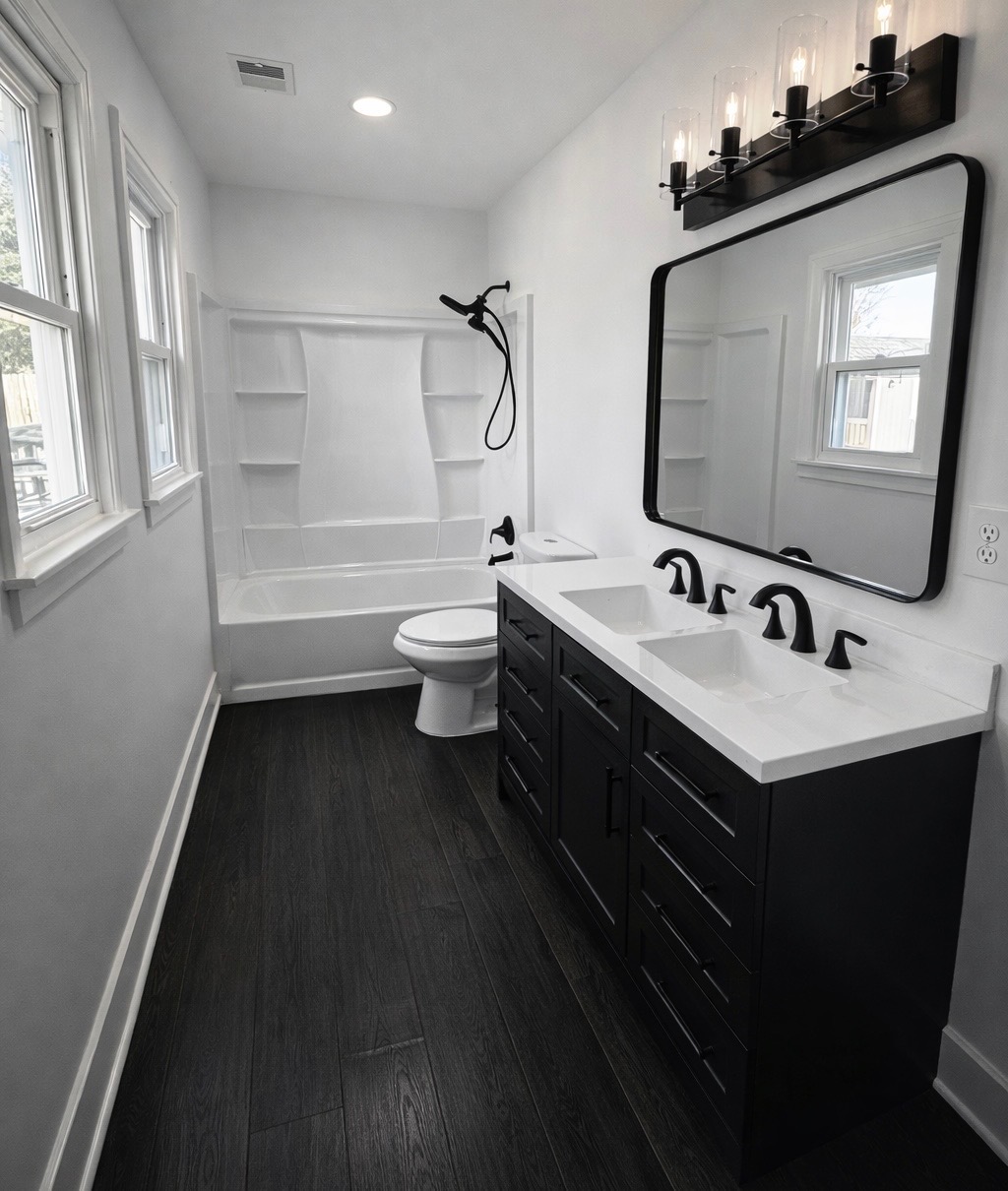 Bathroom remodel with black double vanity, dark flooring, and matte black fixtures